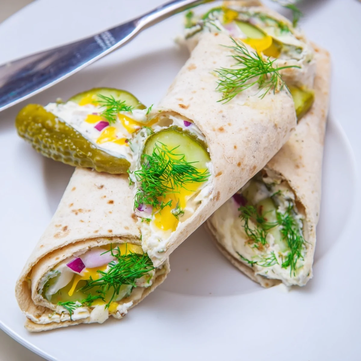 Crispy pickle-in-a-blanket rolls, creamy cheese, and fresh dill for tasty snacking.  
