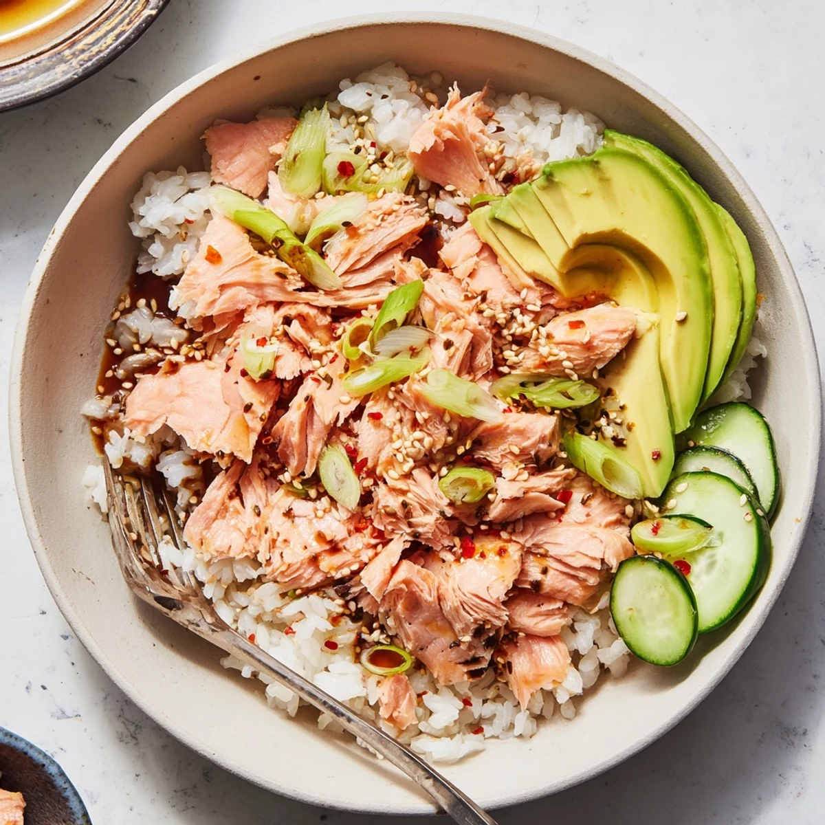 Leftover Salmon & Rice Bowl garnished with fresh avocado and cucumber slices.  