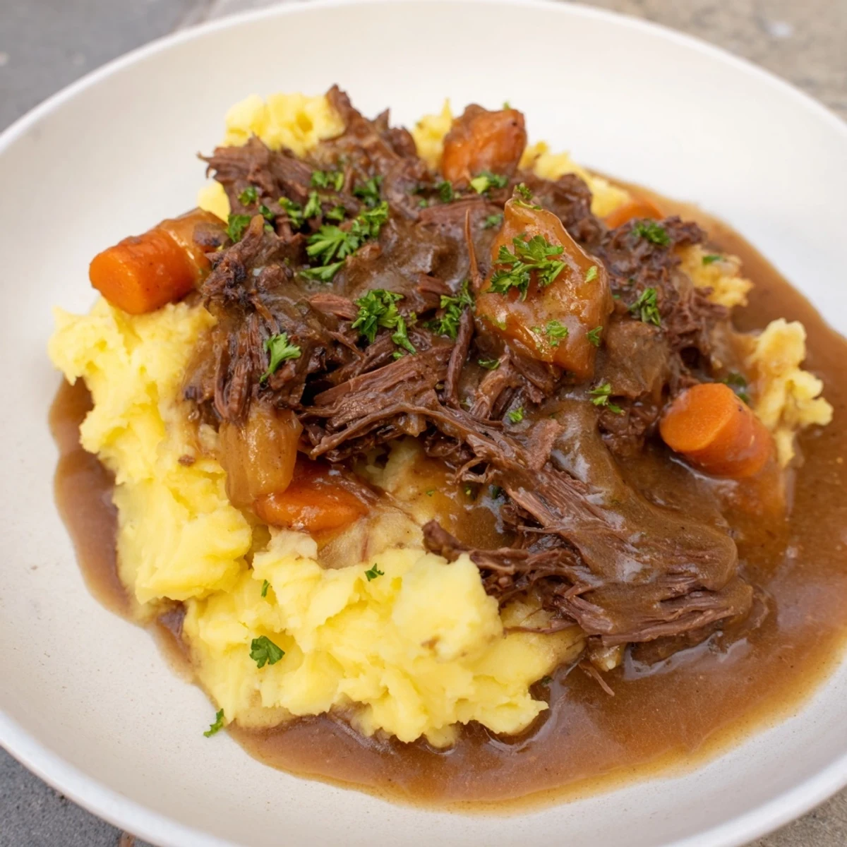 Tender slow cooker pot roast with carrots, celery, and mashed potatoes, ready to serve.