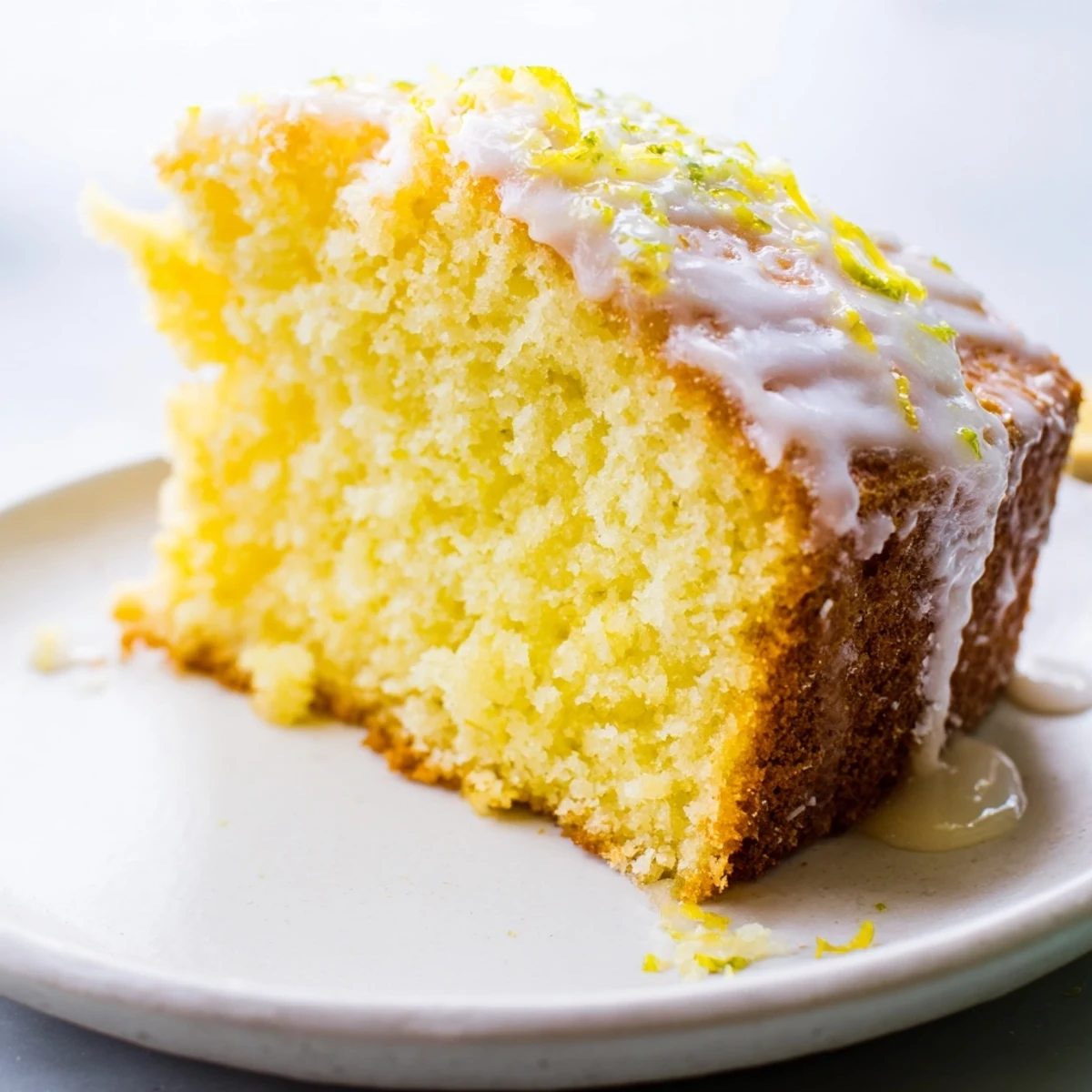 Golden, glazed Lemon Yogurt Cake slice, perfect for a sunny afternoon tea with a refreshing taste.