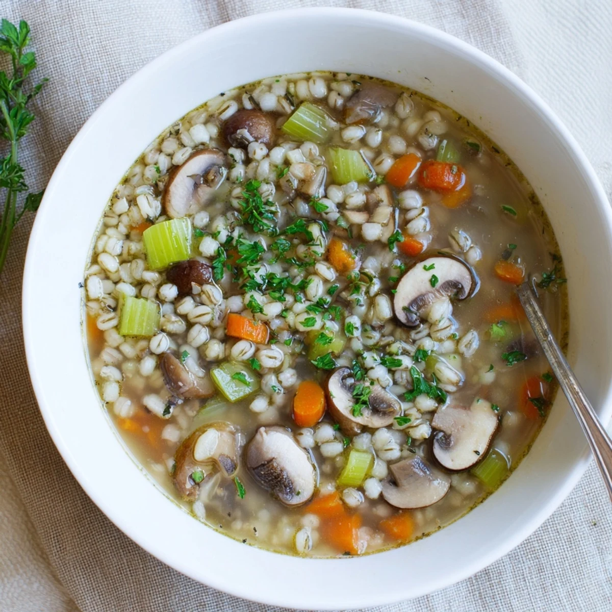 Hearty mushroom and barley soup served in a ceramic bowl, showcasing chewy barley and savory mushrooms in a rich broth.