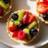 Freshly baked Mini Fruit Tartlets arranged beautifully, offering a mix of textures and bright fruit flavors.