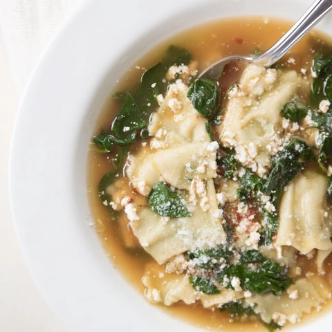 A comforting bowl of lasagna soup topped with melted parmesan and fresh spinach.  