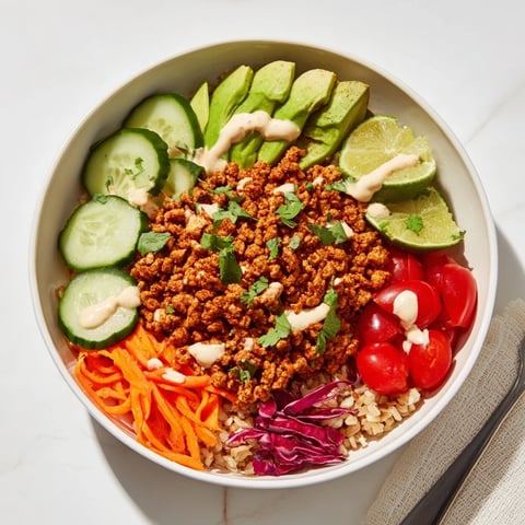 A colorful plant-based meat bowl topped with fresh vegetables and zesty lime.  