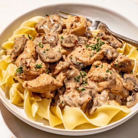 Creamy Chicken Stroganoff served over tender egg noodles with fresh parsley garnish.  