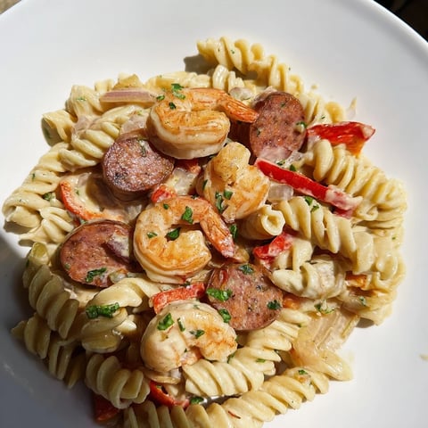 Steaming Cajun sausage and shrimp Alfredo pasta skillet, a creamy, flavorful American comfort food.