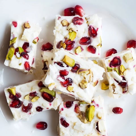 Vibrant frozen yogurt bark with pomegranate, pistachios, and creamy yogurt ready to enjoy.
