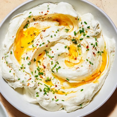 Creamy whipped ricotta dip swirled with vibrant hot honey, perfect for dipping crusty bread slices.