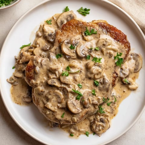Golden-brown Stove Top Pork Chops swimming in creamy mushroom sauce, perfect for a cozy supper.