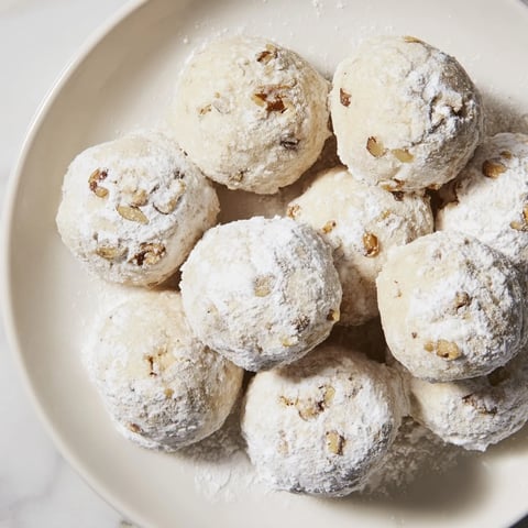 Golden-crusted Budget-Friendly Snowball Cookies, ready to eat, dusted with powdery sugar for a festive look.