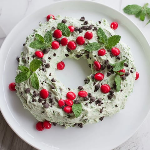 Festive Mint Chocolate Chip Dip Wreath, a creamy dessert decorated with mint and red candies.