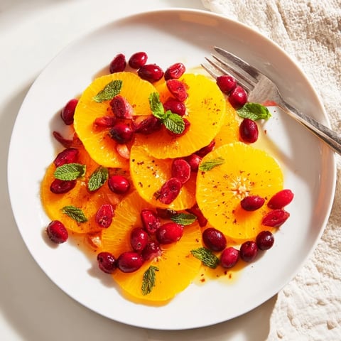 Bright, juicy orange slices and cranberries on a platter: a simple, refreshing winter fruit salad.