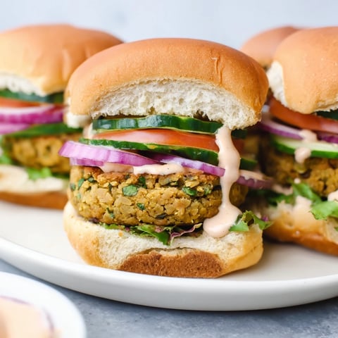 Golden-brown Baked Falafel Sliders, overflowing with fresh vegetables and creamy tahini sauce, ready to eat.