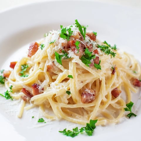 Golden crispy bacon pieces in a creamy garlic bacon pasta, ready to serve with fresh parsley.