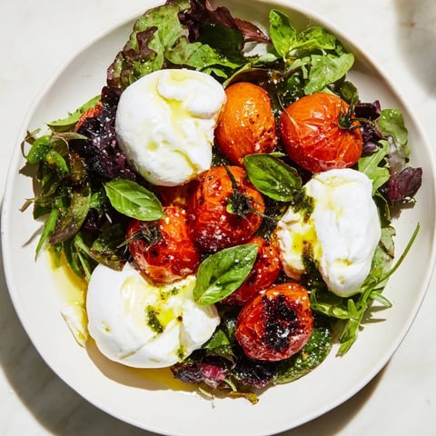 A colorful Charred Tomato Salad with creamy burrata, drizzled with fragrant basil oil.