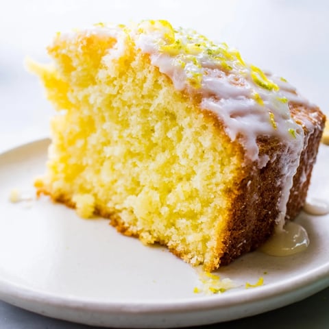 Golden, glazed Lemon Yogurt Cake slice, perfect for a sunny afternoon tea with a refreshing taste.