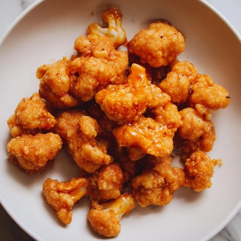 Golden-brown Buffalo Cauliflower Bites ready to be dipped and enjoyed with refreshing carrot sticks.