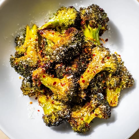 Golden, crispy Garlic Parmesan Roasted Broccoli, ready to serve with extra Parmesan cheese sprinkled on top.