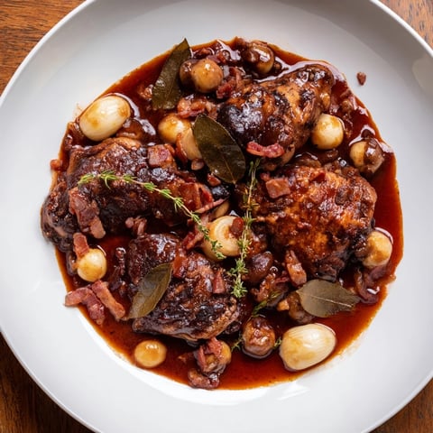 Tender chicken in rich red wine sauce, part of a flavorful Coq au Vin, ready to eat.