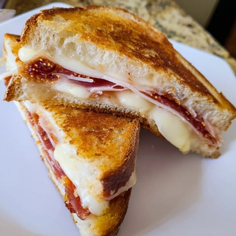Golden, toasted Crispy Prosciutto & Fig Panini oozing with melted fontina, ready for a delicious bite.