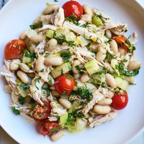 A vibrant bowl of Lemony White Bean Chicken Salad features tender chicken, creamy white beans, and crisp celery in a tangy dressing.