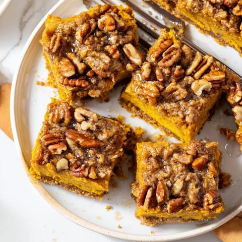 Maple-sweetened Cinnamon Pumpkin Bars, drizzled with syrup, nuts, sliced, ready to serve.