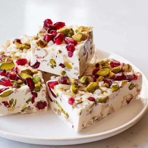 Homemade frozen yogurt bark, showcasing bright red pomegranate seeds with chopped pistachios.