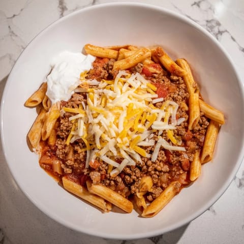 Golden, bubbly Easy Beef Enchilada Pasta, a one-pot meal, with melted cheddar and sour cream.