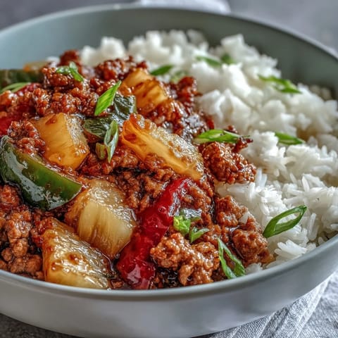 Golden-brown ground turkey, crisp red and green bell peppers, and sweet pineapple chunks are tossed in a glossy sweet-and-sour sauce in a hot skillet with fluffy jasmine rice.