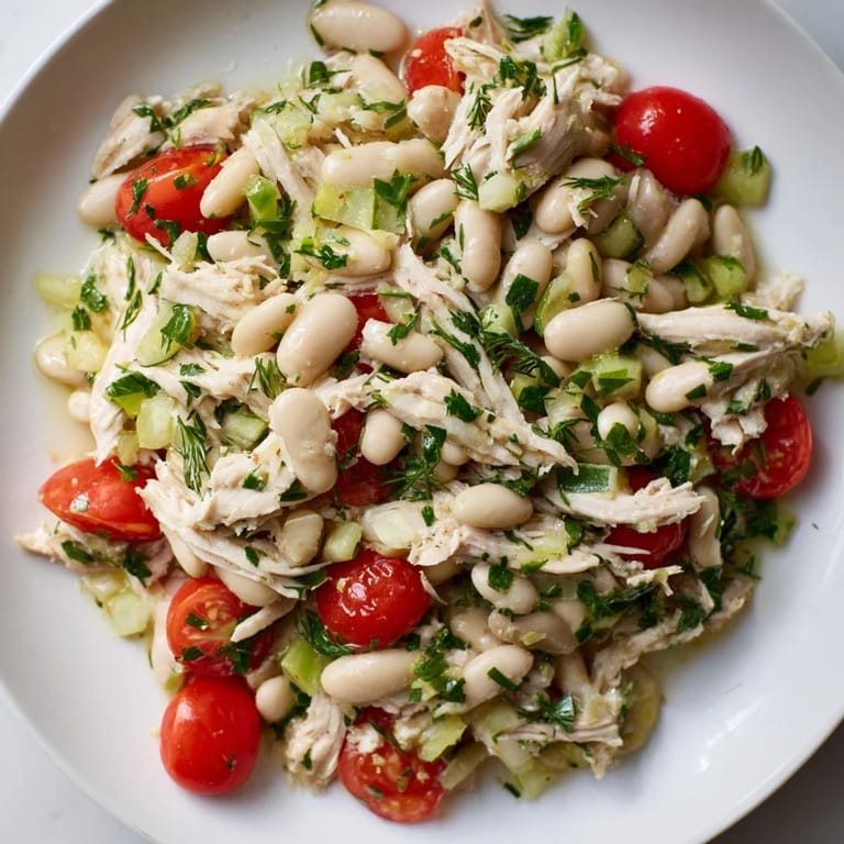 Spoonful of Lemony White Bean Chicken Salad with bright herbs, cherry tomatoes, and lemon zest, ready for a light lunch.