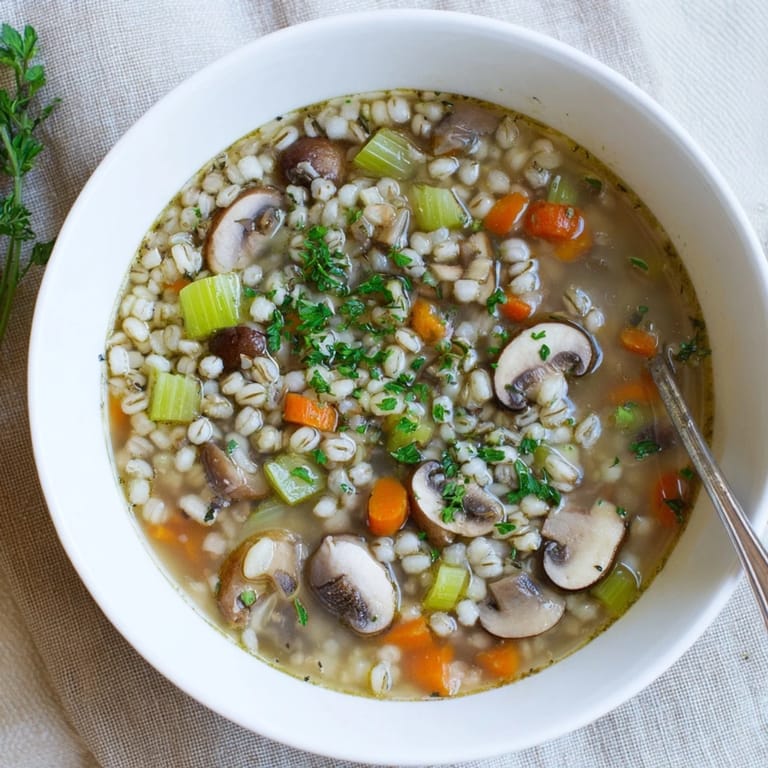 Hearty mushroom and barley soup served in a ceramic bowl, showcasing chewy barley and savory mushrooms in a rich broth.