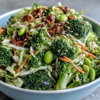 Fresh broccoli crunch salad with vibrant veggies and zesty Asian-inspired dressing, topped with toasted sesame seeds for extra flavor and texture.