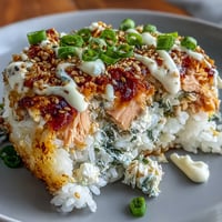 1. A colorful salmon sushi bake casserole with creamy seafood filling, seasoned rice, and vibrant toppings, served with crispy seaweed sheets.  