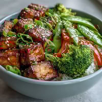 A colorful vegan stir-fry with golden crispy tofu, vibrant broccoli, and snap peas glazed in rich teriyaki sauce.
